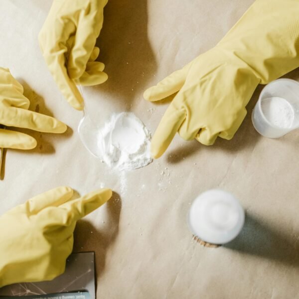 A top view of hands in latex gloves conducting a powder experiment on brown paper.